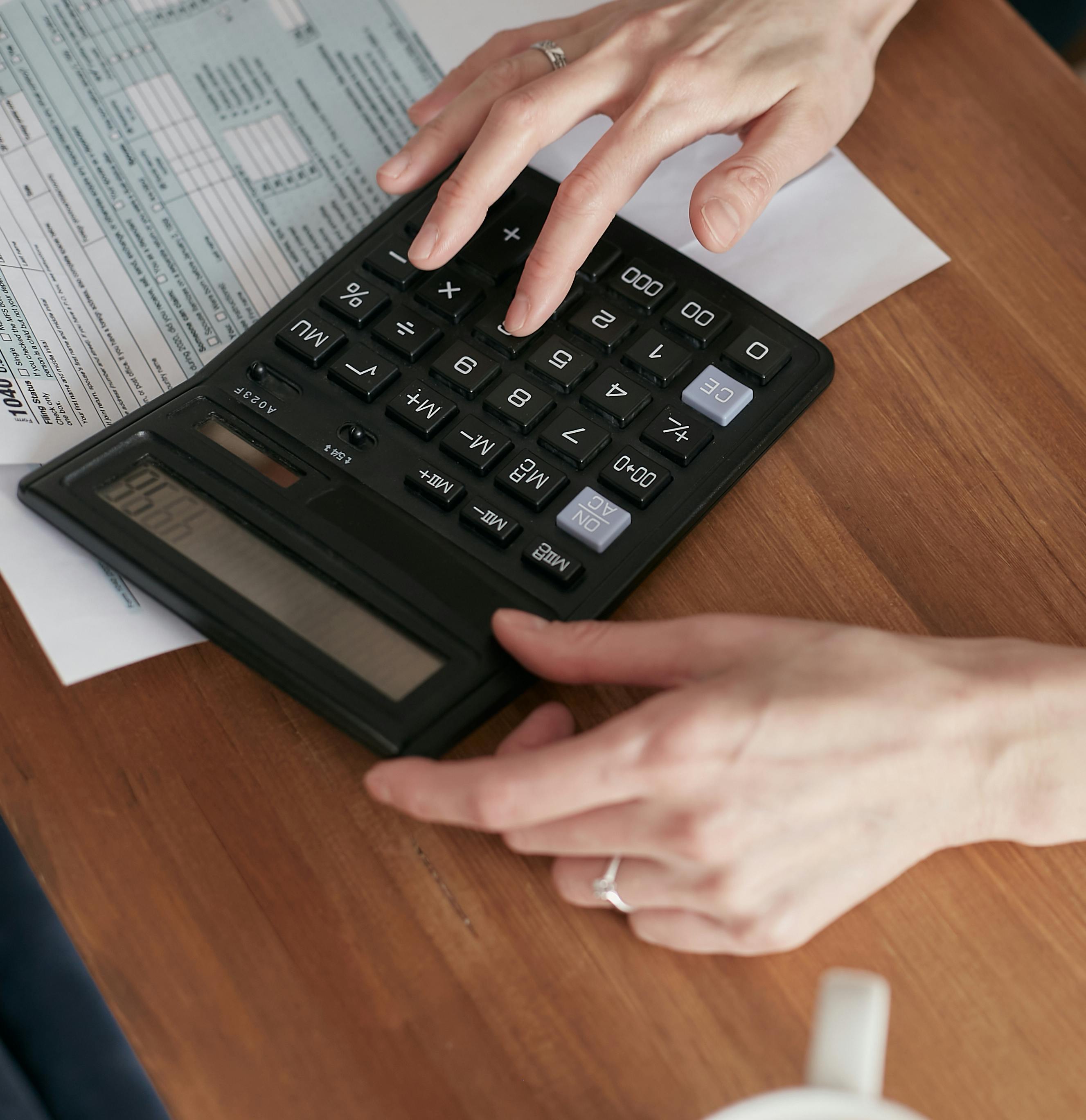 Person reviewing financial documents on a laptop with calculator on desk